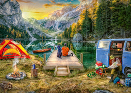 A serene jigsaw puzzle scene featuring a scenic campsite by a tranquil lake. The image showcases a person and a dog sitting on a wooden dock, gazing at the surrounding mountains and trees at sunset. There is a vibrant tent, a canoe on the water, a campfire with smoke, and a camper van in the background, creating a cozy outdoor atmosphere perfect for puzzle enthusiasts.