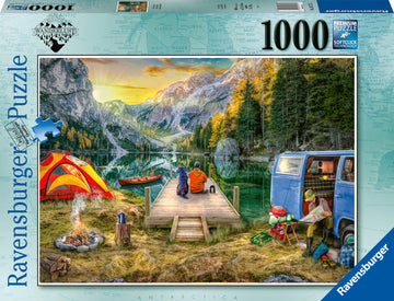 A vibrant Ravensburger puzzle box showcasing a peaceful campsite scene. Two people sit on a wooden dock by a serene lake, surrounded by majestic mountains and lush trees. A bright red and orange tent, a campfire, and a blue VW van are visible, creating a cozy outdoor atmosphere. The puzzle contains 1000 pieces and features premium quality with soft-click technology for easy assembly.