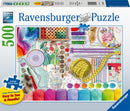 The Needlework Station 500 pc Large Format Puzzle by Ravensburger features a vibrant and detailed arrangement of sewing supplies. The image showcases colorful spools of thread, knitting needles, measuring tape, buttons, pins, and fabrics, all thoughtfully organized. The large format makes it easy to see and handle each piece, ideal for puzzle enthusiasts. SoftClick technology ensures a perfect fit for each puzzle piece.