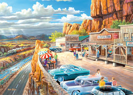 The Scenic Overlook 500 pc Large Format jigsaw puzzle by Ravensburger features a vibrant artwork depicting a picturesque viewpoint. The scene showcases a busy roadside with colorful retro cars, people dining under striped umbrellas, a scenic river, and a passing train amidst stunning mountainous landscapes. This nostalgic illustration captures a lively atmosphere, perfect for puzzle enthusiasts who appreciate detailed artistry and scenic views.