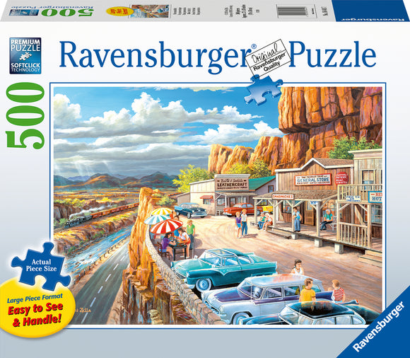 Ravensburger Scenic Overlook 500 pc large format jigsaw puzzle featuring a vibrant scene of a historic roadside with classic cars parked, a restaurant, a general store, and people enjoying the view of the mountains and river in the background. The puzzle emphasizes large piece size for easy handling.