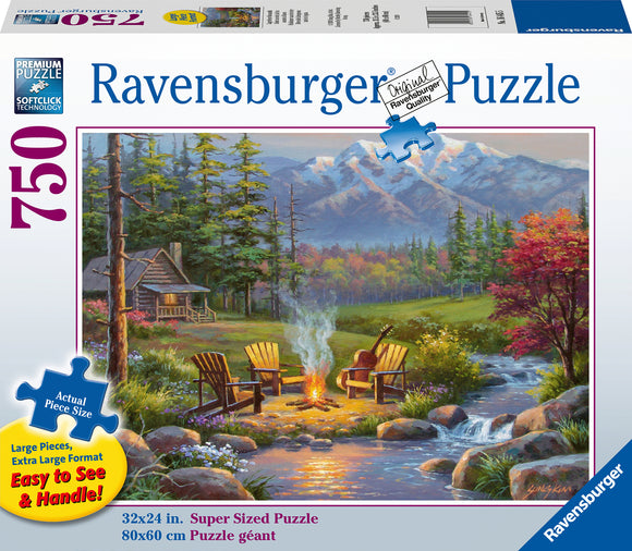 A 750-piece jigsaw puzzle titled Riverside Livingroom by Ravensburger. The image showcases a serene outdoor scene featuring two wooden chairs by a campfire, surrounded by lush greenery and mountains in the background. The puzzle's box displays the dimensions of 32x24 inches and highlights its large, easy-to-handle pieces.