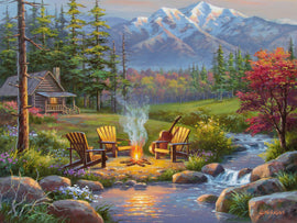 Ravensburger Riverside Livingroom 750-piece jigsaw puzzle featuring a tranquil landscape scene. The image showcases a cozy log cabin by a stream, surrounded by lush greenery, colorful flowers, and majestic mountains in the background. A warm campfire sits between wooden chairs, with a guitar resting on one of them, evoking a peaceful outdoor ambiance.