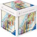 Puzzle Moment: NYC 99 pc Jigsaw Puzzle by Ravensburger. The puzzle box features a colorful illustration of Manhattan, highlighting iconic skyscrapers, streets, and green spaces. A perfect activity for puzzle lovers and city enthusiasts.