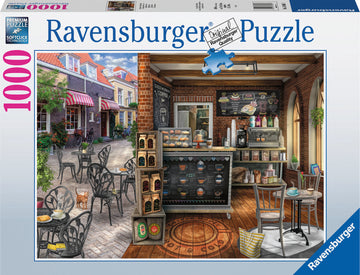 A beautifully illustrated 1000 piece jigsaw puzzle featuring a quaint café scene. The puzzle showcases a charming outdoor seating area with black chairs and tables, a sidewalk lined with greenery, and a cozy café interior adorned with chalkboard menus, coffee machines, and pastries. A playful cat is seen near the tables, adding to the inviting atmosphere.