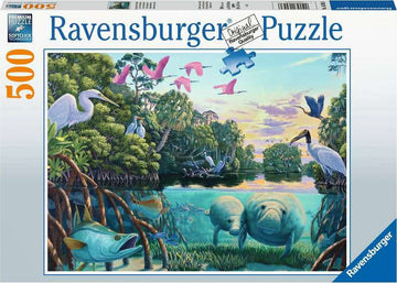 Ravensburger 500 piece jigsaw puzzle titled 'Manatee Moments' featuring a serene aquatic scene. The artwork depicts manatees swimming in a lush river surrounded by various birds and vegetation, with soft sunlight illuminating the landscape.