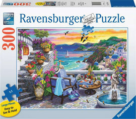 The Santorini Sunset jigsaw puzzle by Ravensburger features a vibrant scene of a coastal terrace adorned with colorful flowers, comfortable chairs, and a table set for leisure. The background showcases a stunning sunset over the sea, with hills, sailing boats, and traditional buildings typical of Santorini, Greece. The puzzle has 300 large pieces that are easy to see and hold, making it perfect for families and puzzle enthusiasts alike.