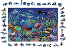 A colorful 500-piece jigsaw puzzle titled 'WOOD: Under the Sea' by Ravensburger. The completed puzzle features an underwater scene filled with various marine life, including fish, turtles, sharks, and coral, set against a deep blue ocean background. The puzzle pieces showcase detailed illustrations of sea creatures and underwater elements, making it a vibrant and engaging visual experience.