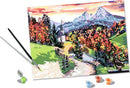 CreArt Beautiful Bavaria DIY kit showcasing a picturesque landscape of vibrant autumn colors, with a winding path, church steeple, and majestic mountains in the background. The kit includes a paintbrush, paint pots, and a canvas featuring outlines for easy painting.