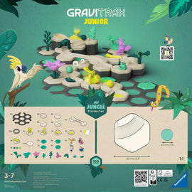 GraviTrax Junior Starter-Set Jungle by Ravensburger featuring colorful hexagonal tiles, jungle-themed pieces including plants, a parrot, and a snake. Designed for kids aged 3-7, the set promotes creativity and construction skills with 100 pieces. The background is vibrant green with tropical leaves.