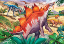 A vibrant jigsaw puzzle featuring a prehistoric scene, showcasing various dinosaurs including a colorful Stegosaurus, a fierce-looking Tyrannosaurus rex, and others, set against a lush, tropical landscape with mountains in the background. The artwork is rich in detail, depicting the dinosaurs among greenery and rocky formations, inviting users into a world of Jurassic adventure and exploration.