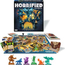 The Horrified Greek Monsters game by Think Fun. The box shows intricate artwork with Greek monsters and gods. The game board is vibrant, featuring locations from Greek mythology with colorful monster figures in various poses, player components like cards and dice, and an overview of the game setup.