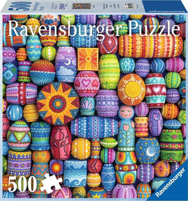A colorful jigsaw puzzle featuring a vibrant array of painted beads in various patterns and designs. The puzzle includes 500 pieces and is produced by Ravensburger. The background showcases a lively mix of colors including bright pinks, blues, greens, and yellows.