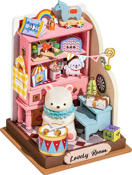 A charming DIY Childhood Toy House by Robotime, featuring a colorful display with a pink shelf filled with fun toys, including a blue horse, decorative flags, and a cute bear figurine next to a wooden table. The scene is bright and playful, showcasing various miniature items that spark creativity and nostalgia.