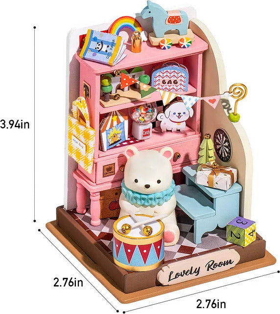 A detailed image of the DIY Childhood Toy House, a colorful miniature room set by Robotime. It features a pink shelving unit filled with playful items like books, colorful bags, and a cute bear figurine. The cozy setting includes a blue chair, a patterned floor, and decorative elements like a small clock and a drum. Sized at 3.94in height, 2.76in width, and 2.76in depth, this toy house captures a charming and whimsical atmosphere suitable for kids.