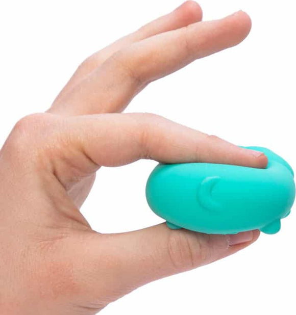 A hand holding the Teenie Funky Pups Nee Doh, a squishy, colorful fidget toy shaped like a cartoonish puppy. The toy is teal and has a happy expression, designed for squeezing and relaxation.