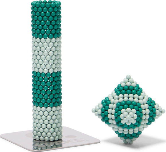 Speks Elements: Marine, a creative and colorful magnetic building set featuring teal and white spheres. The image displays a tall, cylindrical structure made with the spheres alongside a diamond-shaped configuration, all resting on a branded base.