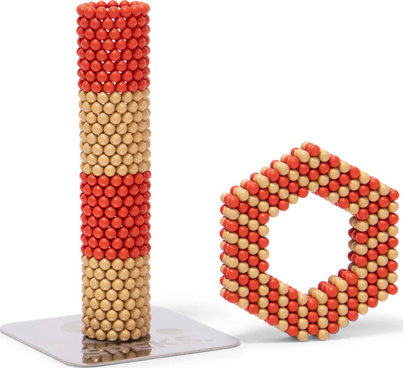 SPEKS Elements: Solar features colorful magnetic balls designed to be stacked and shaped into various forms. A tall, vertical column stands beside a hexagonal structure, showcasing the versatility and creativity of the product. The magnetic elements are in red and beige shades, enabling engaging and tactile play.
