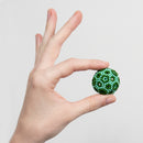 A hand holding a colorful sensory fidget toy, Speks Elements: Terra, featuring a textured surface with green and light blue beads that resemble a small globe.
