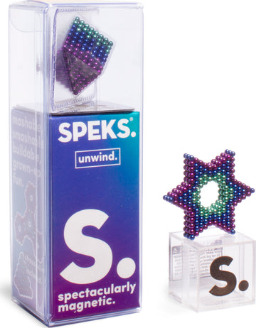 The Speks Unwind Gradient is a colorful magnetic building toy. The product is shown in its clear packaging, with a large purple and green star-shaped arrangement of small magnetic balls on display beside it. The packaging features the brand name SPEKS and highlights that the product is designed for stress relief and creative fun.