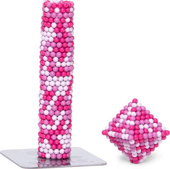 SPEKS Pixel Cheat Code is a colorful building set featuring a tall cylindrical structure made of pink and white spheres, alongside a smaller cubic shape. The set encourages creativity and imaginative play, offering a tactile experience for users to build and explore various forms.