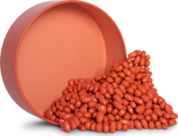 A round coral-colored container tipped over, spilling a pile of small, oblong coral-colored pieces resembling colorful pebbles. The smooth, matte finish of the pieces gives them a tactile, playful quality, ideal for creative activities or fidgeting.