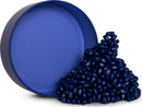 A collection of deep indigo-colored fidget toys spilling out of a round, matte container. The toys have smooth, rounded surfaces and vary in size, creating a playful mound of color.