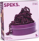 The Crags Matte: Iris by SPEKS is a captivating package featuring a mound of purple, magnetic fidget putty resembling jelly beans, set atop a round purple tin. The vibrant colors invite tactile engagement, perfect for stress relief and endless fidget fun.
