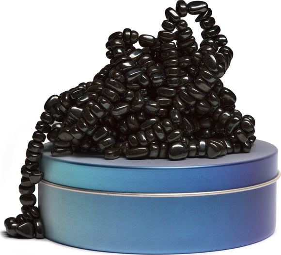SPEKS Crags: Serenity, featuring a heap of glossy black beads resting atop a stylish gradient tin with a smooth surface, ideal for fidgeting and stress relief.