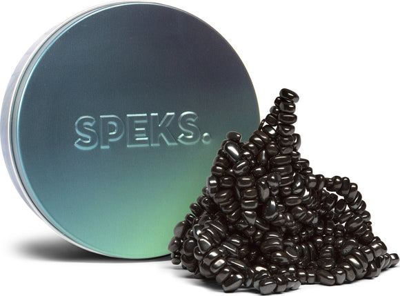 The Crags: Tranquility product by SPEKS features a round metallic tin with the word 'SPEKS' embossed on it. The tin is partially open, revealing a heap of innovative magnetic beads that are glossy black and shaped irregularly. These beads can be molded and shaped to create various designs, providing a satisfying tactile experience for users, ideal for stress relief or creative fun.