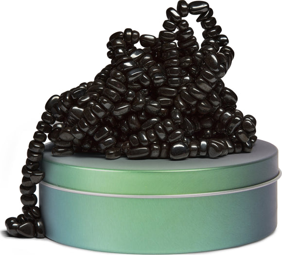 SPEKS Crags: Tranquility is a unique fidget toy featuring a collection of shiny black beads piled on top of a pastel green tin. The design encourages tactile engagement and sensory exploration, making it perfect for stress relief.