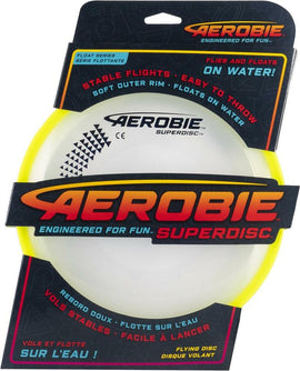 The Superdisc by Spinmaster is a flying disc featuring a soft outer rim for easy throwing. It is designed for stable flights and is capable of floating on water, making it perfect for outdoor fun. The product is displayed in a brightly colored package that emphasizes its features, including its ability to fly and glide effortlessly.