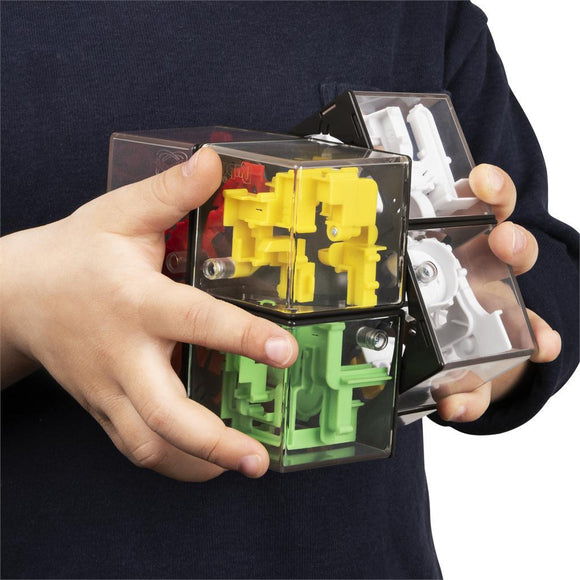 A child holding the Perplexus Rubik's Hybrid, a mechanical puzzle featuring colorful interlocking pieces in yellow, green, red, black, and white. The puzzle showcases a transparent outer shell that reveals the intricate mechanisms inside, encouraging hands-on problem-solving and spatial reasoning.