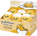 A colorful display box of Gudetama Round Squishies by GUND. The squishies feature Gudetama, the lazy egg character, in various adorable poses, showcasing their soft, plush texture. The box is bright yellow with playful designs and labels for Gudetama, providing an inviting look for fans and collectors.