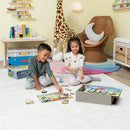Two children playing with the Bluey 4 Wood Puzzles jigsaw set on a soft rug. They are joyfully assembling puzzle pieces featuring colorful characters from the Bluey series. A box containing the puzzles is visible in the background, along with cheerful decor in a bright playroom.