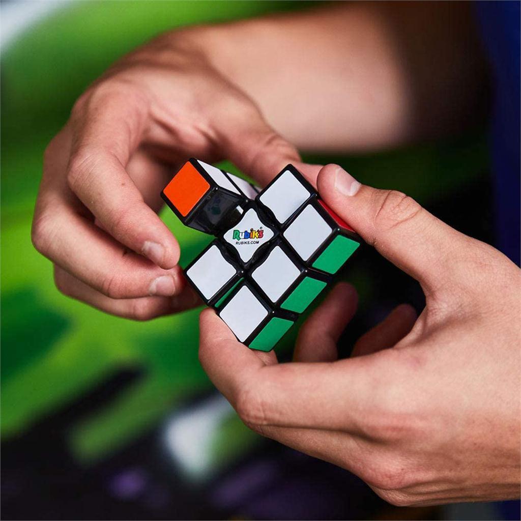 A person holding the Rubik's 3x1 Edge puzzle, a colorful mechanical puzzle featuring a mix of classic Rubik's colors: red, green, blue, orange, yellow, and white. The person is manipulating the puzzle, demonstrating its interactive nature.