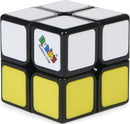 Rubik's 2x2 Apprentice puzzle designed by Spin Master. The puzzle features a glossy black exterior with vibrant white and yellow squares. It is a compact mechanical puzzle ideal for enhancing problem-solving skills and providing hours of entertainment.