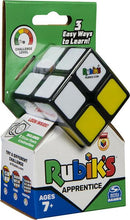 The Rubik's 2x2 Apprentice is a compact mechanical puzzle featuring a vibrant design with a black frame and colorful stickers. It includes instructional materials and challenge levels, making it suitable for ages 7 and up. The packaging highlights three easy ways to learn how to solve the puzzle, appealing to both beginners and experienced players.