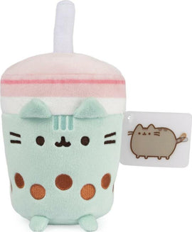 A cute Pusheen-themed plush toy resembling a boba tea cup. The plush features mint green color with light pink and white stripes, and has decorative brown polka dots and Pusheen's face on the front. The plush is topped with a straw and includes a small tag with an illustration of Pusheen.