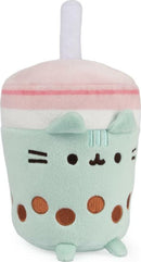An adorable Pusheen Boba Tea Sip Plush by GUND, featuring a soft mint green cup with brown boba dots, a cute cat face, and a pink and white striped lid topped with a straw.