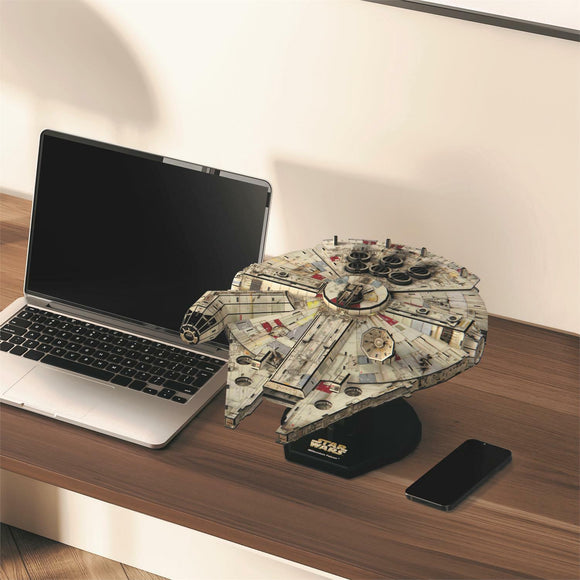A detailed 3D model of the Millennium Falcon from Star Wars, created by 4D Cityscape Inc. The model is displayed on a wooden desk next to a laptop and a smartphone, showcasing intricate design and authentic detailing, perfect for fans and collectors.