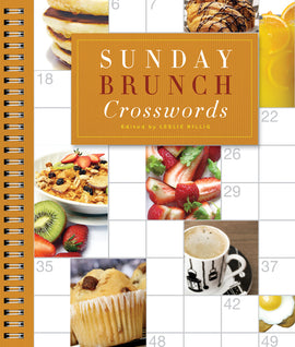A colorful cover of the book 'Sunday Brunch Crosswords', edited by Leslie Billig. The cover features delicious brunch-themed images including pancakes, fruits, and coffee, surrounded by a spiral binding. The title is prominently displayed in a stylish font against a textured, orange background.