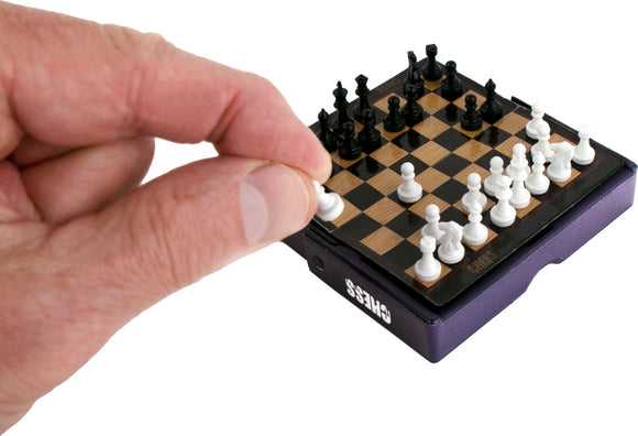 A person holding a white pawn piece and moving it on the World's Smallest Chess mini board, showcasing the intricate and compact design of the game.
