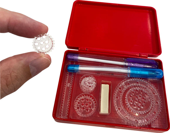 The World's Smallest Spirograph set by Super Impulse displays a hand holding a transparent gear-shaped template. The red case is open, showing various transparent plastic gears and two colorful pens for creating intricate designs. A small white block of modeling material is also included for securing the templates.