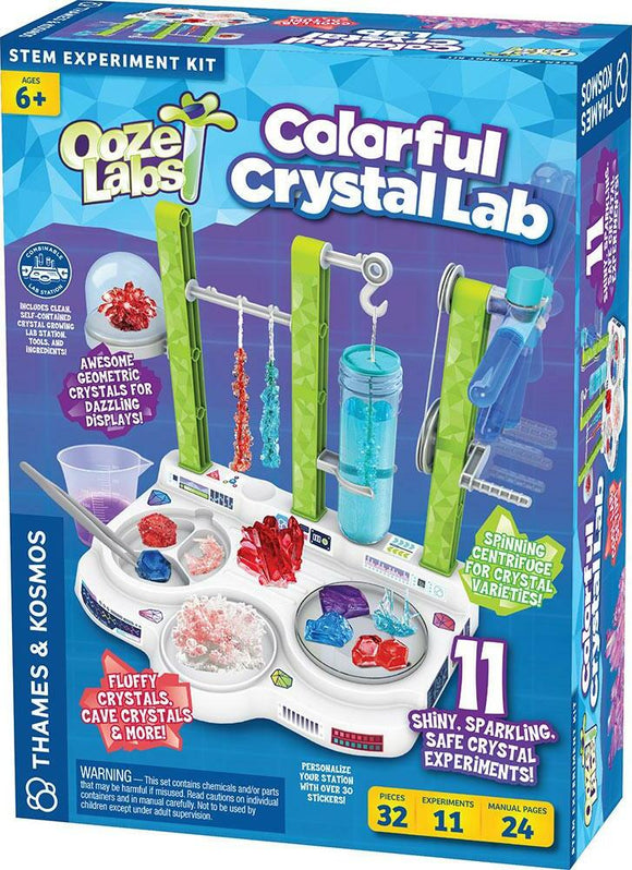 Ooze Labs Colorful Crystal Lab DIY kit by Thames & Kosmos features vibrant packaging showcasing 11 shiny crystal experiments. The kit includes various crystal forming ingredients and tools organized on a table station. Colorful, fluffy crystals are displayed in containers, and emphasizes STEM learning for ages 6 and up.