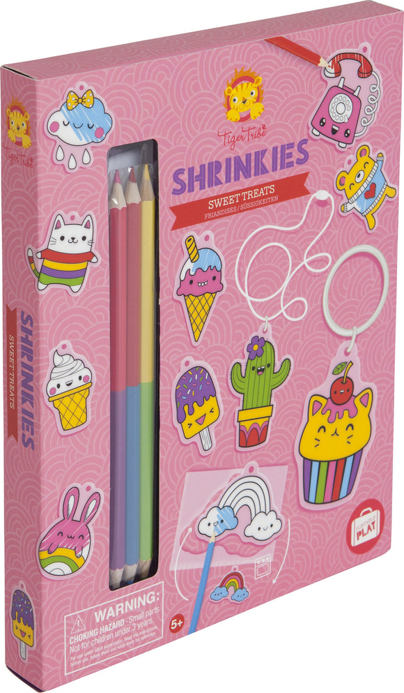 Tiger Tribe Sweat Treats Shrinkies DIY kit. The packaging features colorful illustrations of ice cream cones, cupcakes, and cute animals. Includes colored pencils for customization. Ideal for creating fun, whimsical charms and keychains.