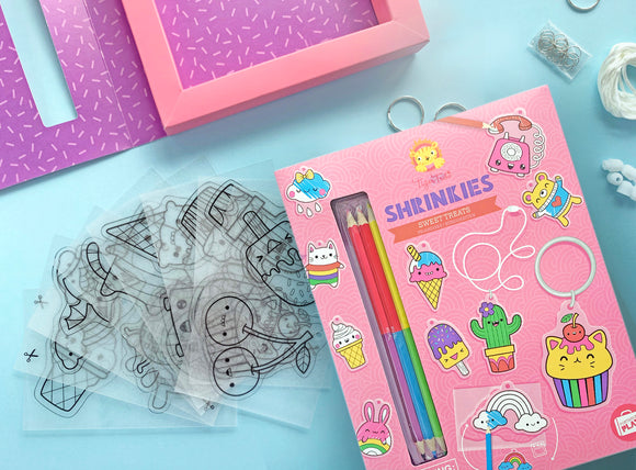 Tiger Tribe's Sweat Treats Shrinkies DIY kit, featuring colorful pencils, outlined plastic sheets with fun food-themed designs, and crafting supplies. Ideal for creative kids to design and make custom charms and accessories.