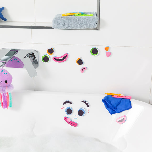 A colorful set of bath face stickers arranged in a playful manner on a white tiled bathroom wall and bathtub. The stickers include various eyes, mouths, and facial features, inviting creativity and fun during bath time. Nearby, there are colorful bath crayons and a plush octopus toy.