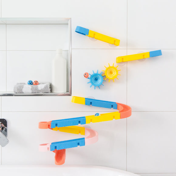 The Waterslide Marble Run by Tiger Tribe features a vibrant, modular design with blue, yellow, pink, and orange components. Set against a tiled wall, the run showcases various twists and turns, with colorful balls ready to roll down. Includes fun interactive elements like spinning gears and suction cups for attachment.