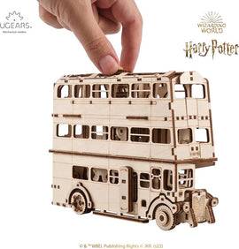 A person holds the Ugears 3D Knight Bus, a mechanical DIY model made of wood, designed for assembly and showcasing intricate details like windows and wheels.